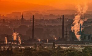 Eine Fabrik bei Sonnenuntergang, die in der Abenddämmerung Rauch ausstößt.