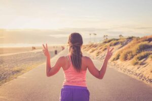 Eine Frau genießt einen Lauf am Strand bei Sonnenuntergang.