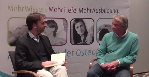 Zwei Männer sitzen auf Stühlen und reden miteinander, während sie eine Osteopathiebehandlung in Hamburg suchen.