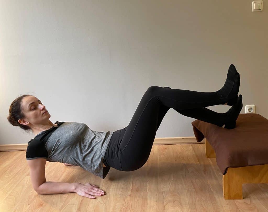 Eine Frau führt auf einem Holzboden eine Sportosteopathie-Übung durch.