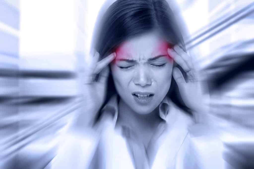 Eine Frau hält sich vor Schmerzen den Kopf, nachdem sie sich wegen ihrer Kopfschmerzen einer Osteopathie-Hamburg-Behandlung unterzogen hat.