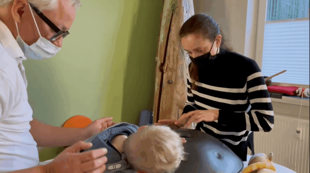 Eine Frau mit Maske kümmert sich in Hamburg um ein Baby auf einem Tisch.