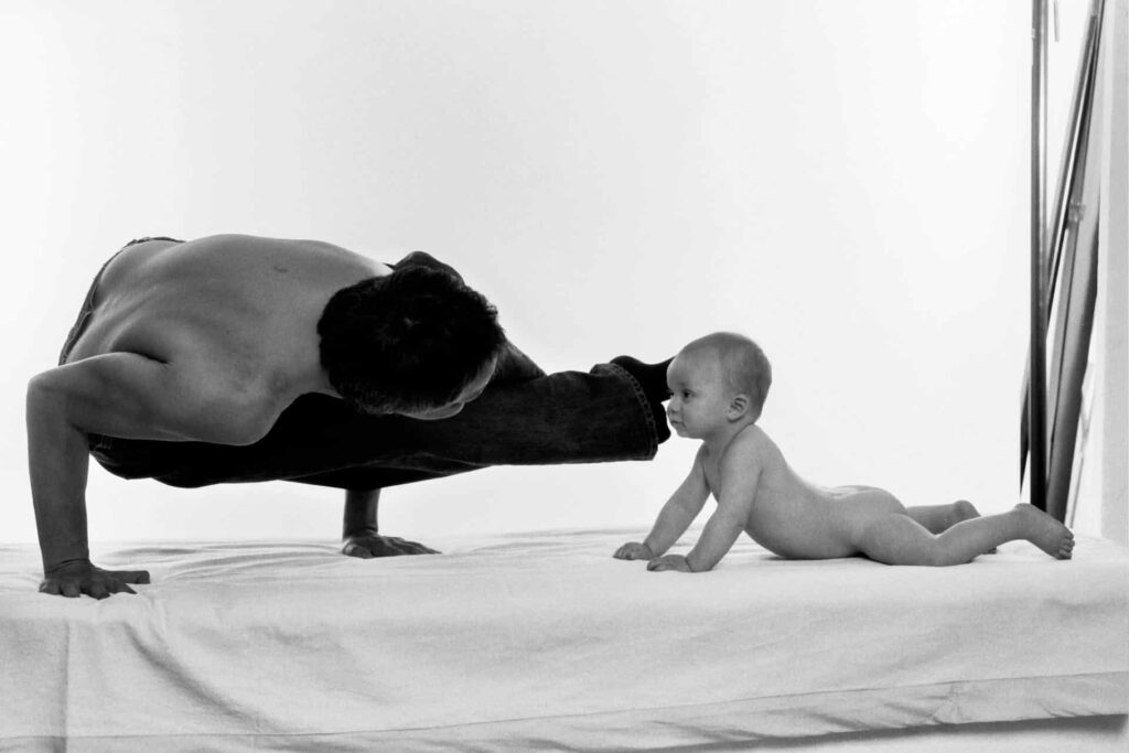Ein Mann und ein Baby machen Yoga auf einem Bett und suchen nach den Vorteilen der Osteopathie in Hamburg.