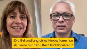 Geteilter Videoanruf mit zwei Personen im Gespräch. Links eine lächelnde Frau mit langen braunen Haaren. Rechts eine Person mit kurzen weißen Haaren und Brille. Unten in einem gelben Textfeld steht: „Die Behandlung eines Kindes kann nur als Team mit den Eltern funktionieren.“.